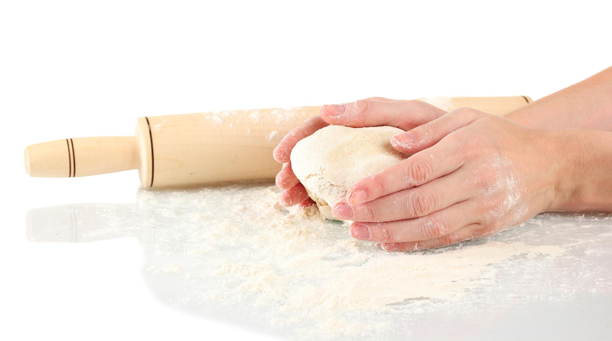 Hands kneading dough on wooden board